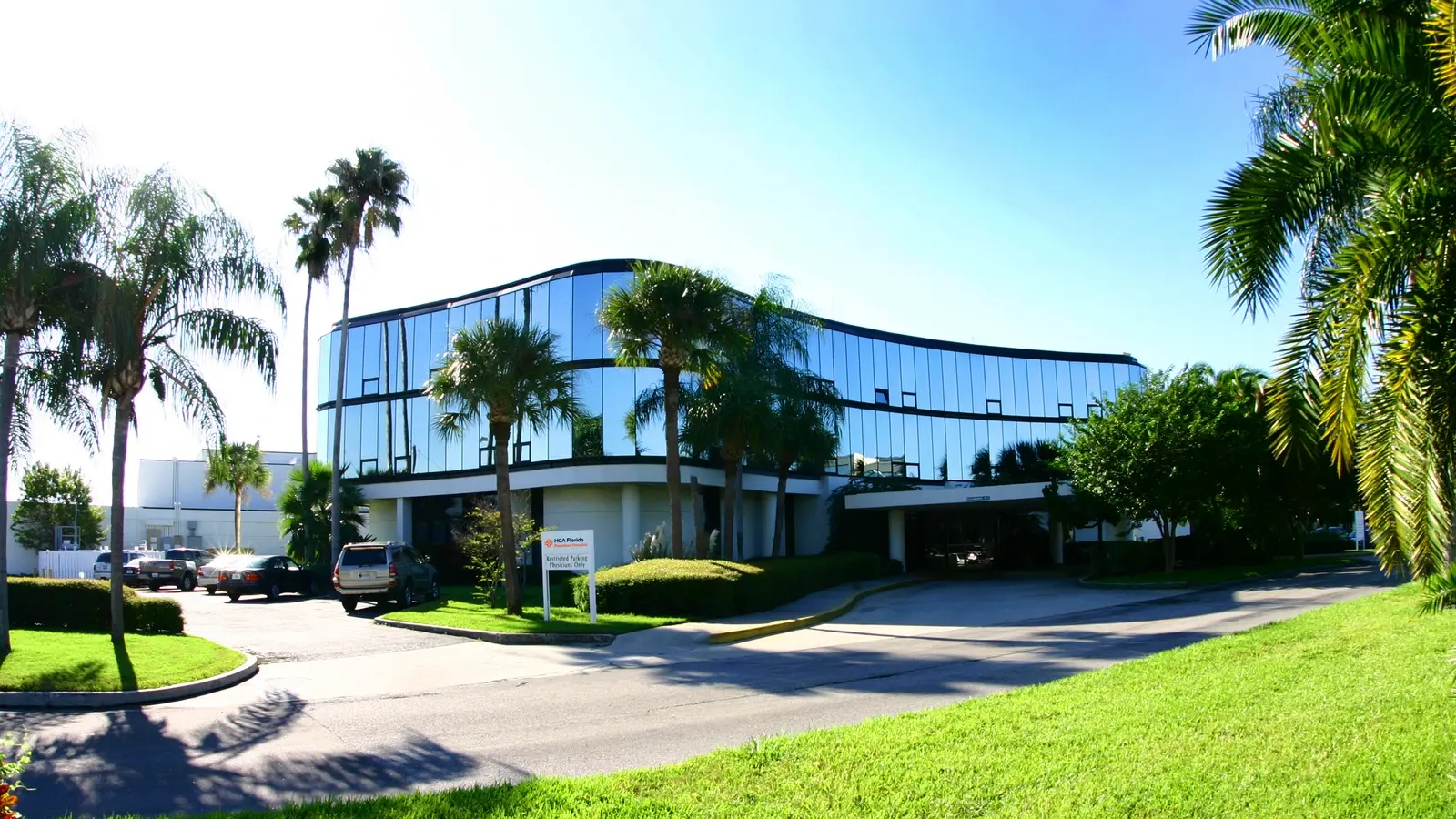 Exterior of Pasadena Hospital entrance drive. A two story building with reflective blue windows framed in black.