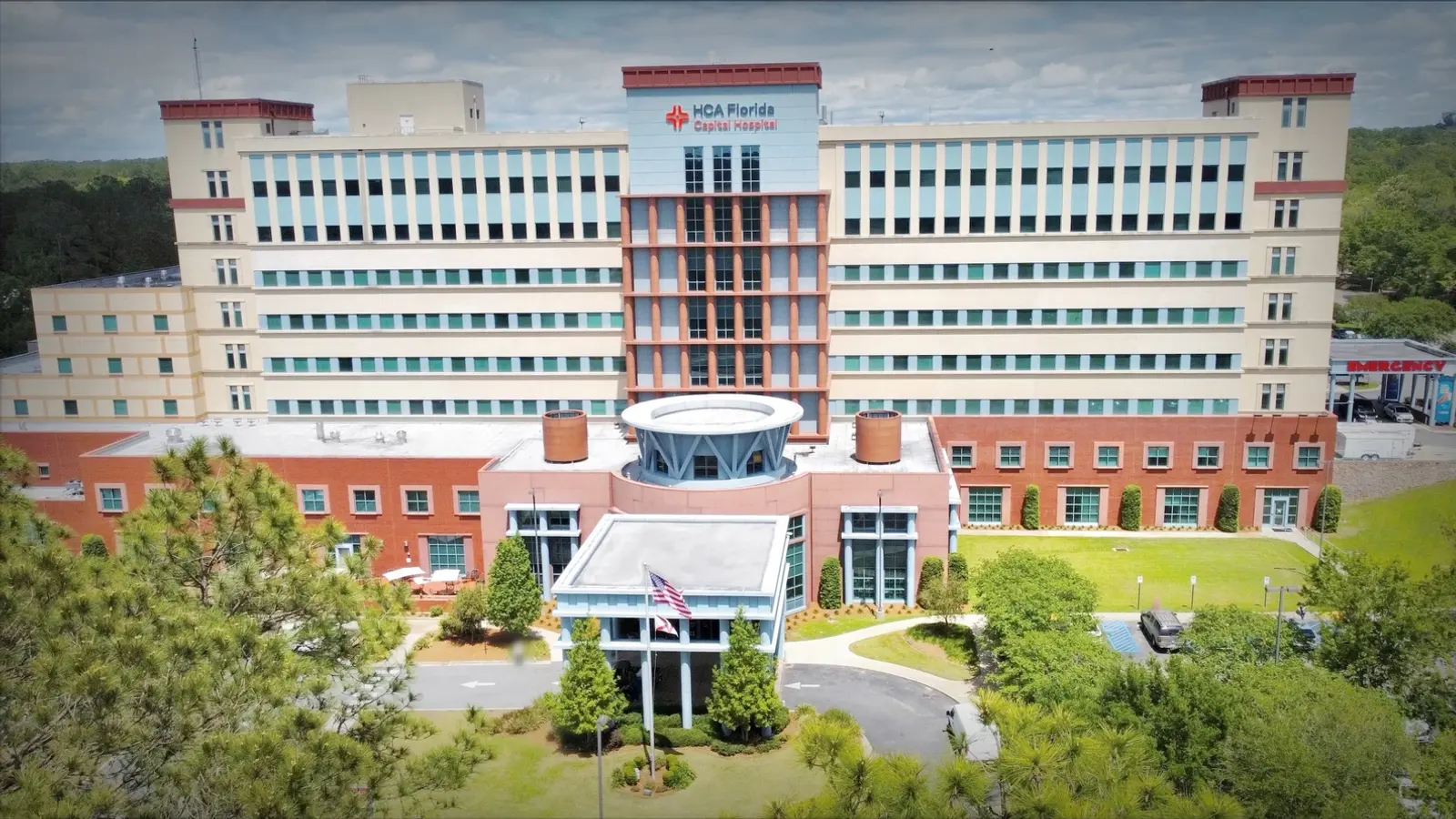 Capital Hospital photograph taken from a drone. Trees and a green lawn and an American flag on a flagpole in front of the entryway overhang.