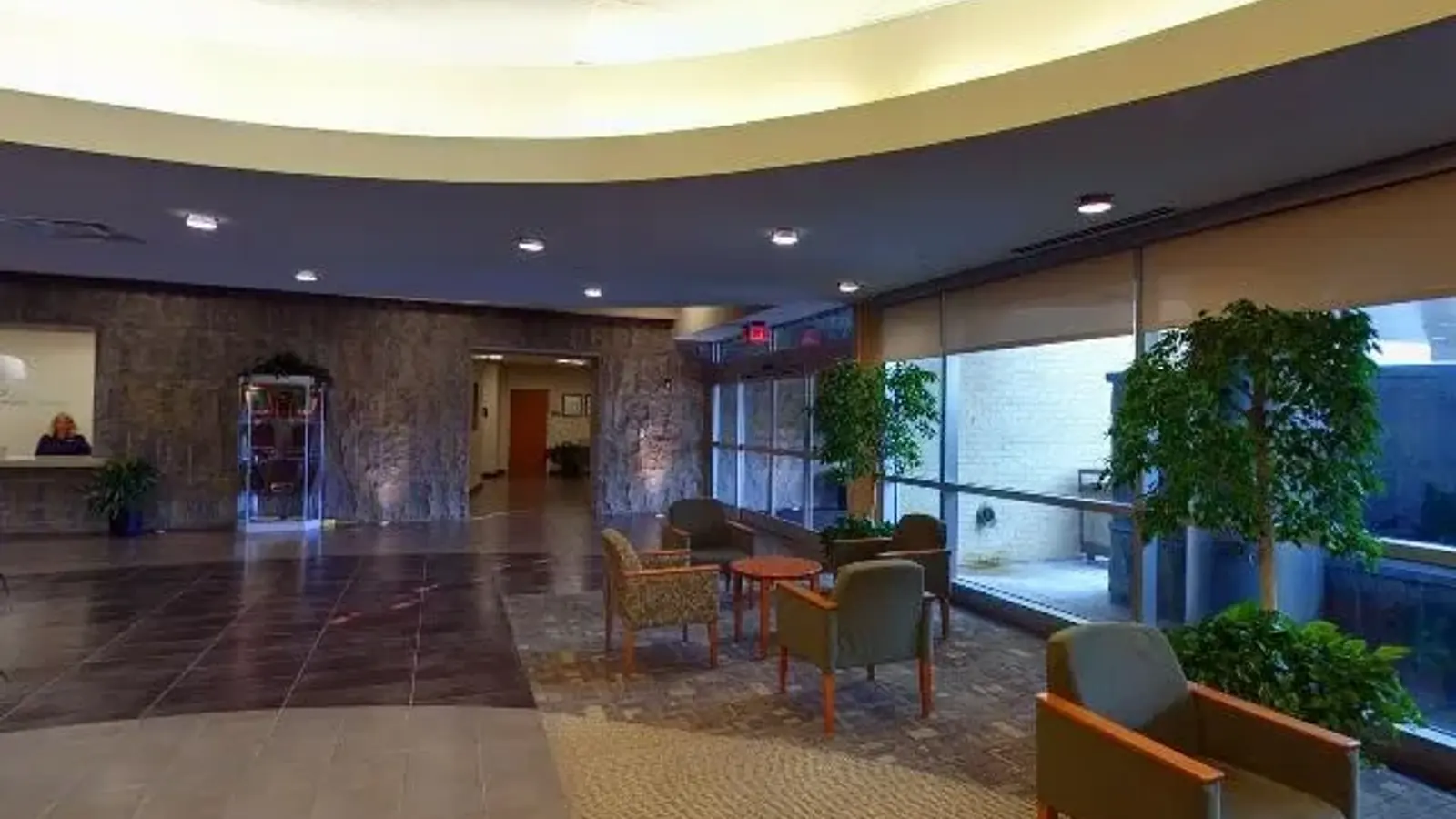 Hospital lobby with cove-lit ceiling, stone reception wall and waiting-area seating