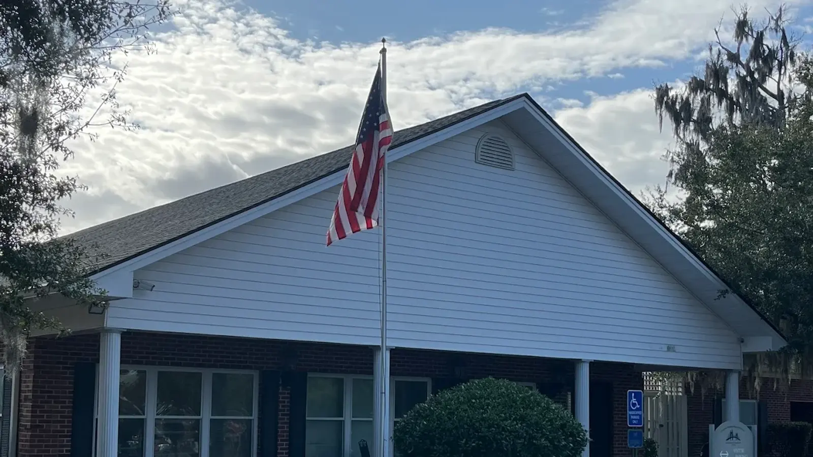 Single-storey brick and white clapboard building with a flagpole at the visitor entrance
